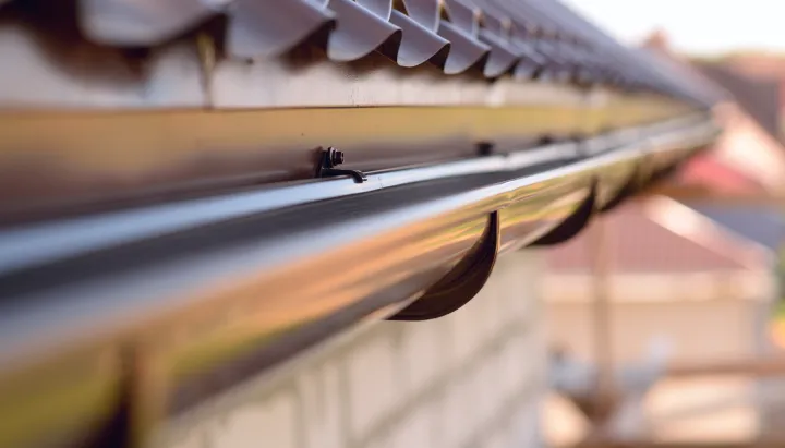Close-up of clean aluminum rain gutter with drip edge on residential roofline.